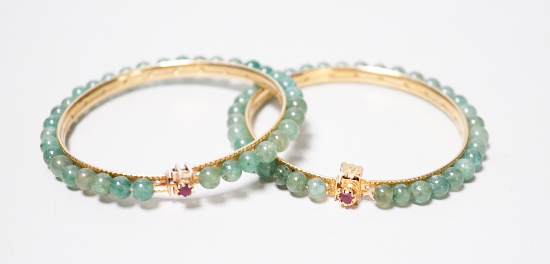 A pair of yellow metal and jade bangles, 7.2cm diameter
